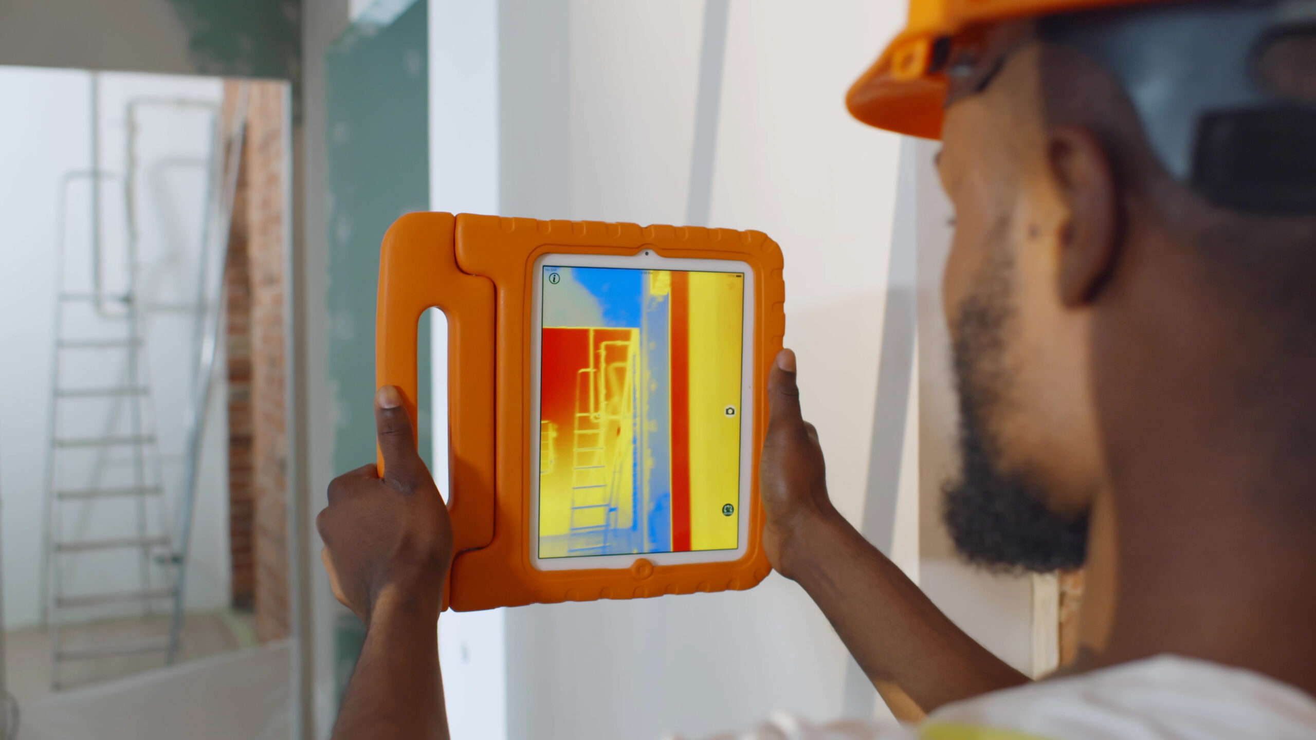 professional worker doing analysis of heat on wall with thermal imaging camera